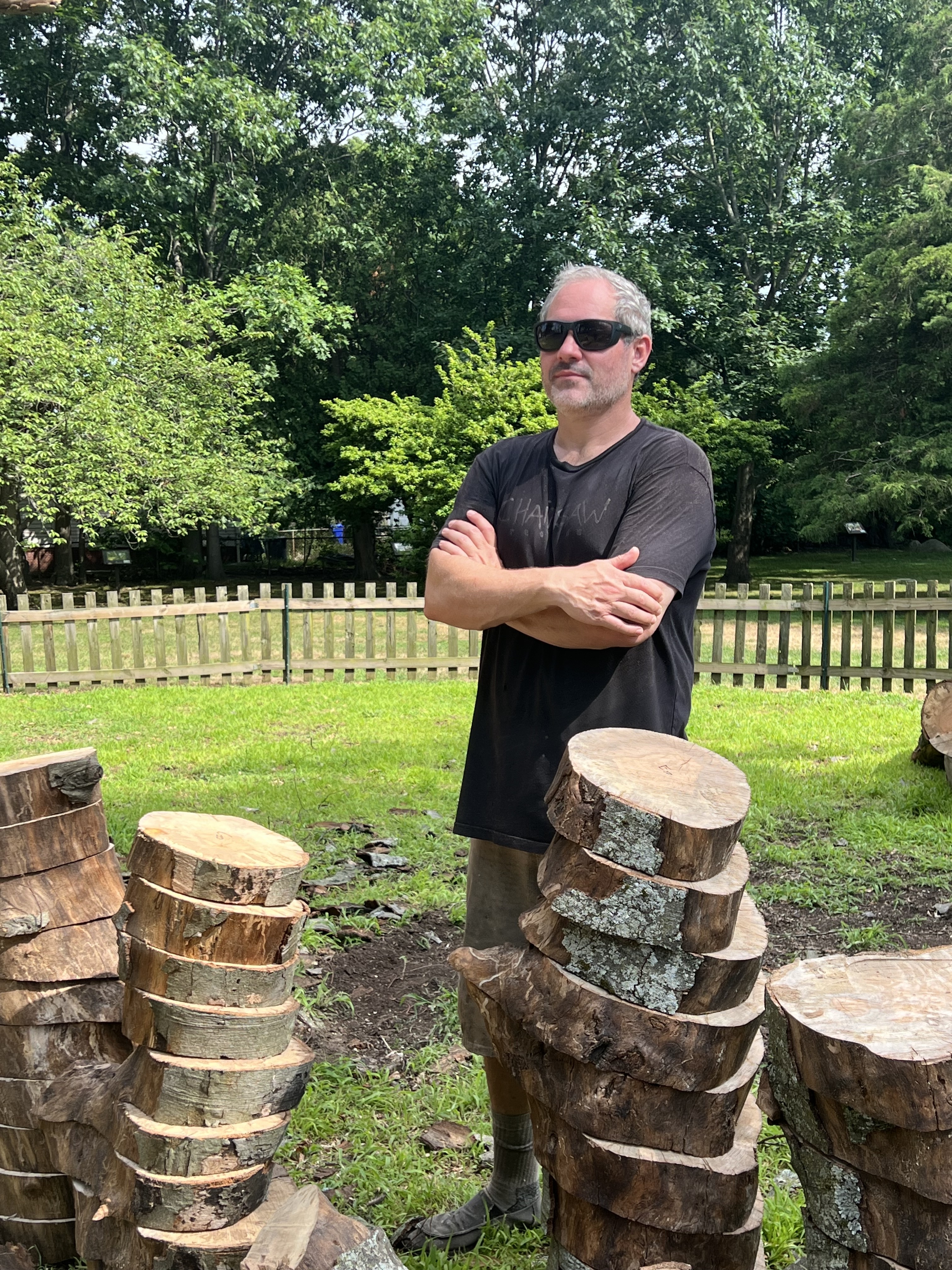 Sculptor Anthony Heinz May near beach tree and piles of limb slices